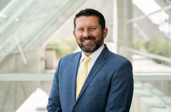 Shawn VanDiver headshot, gray suit and gold tie